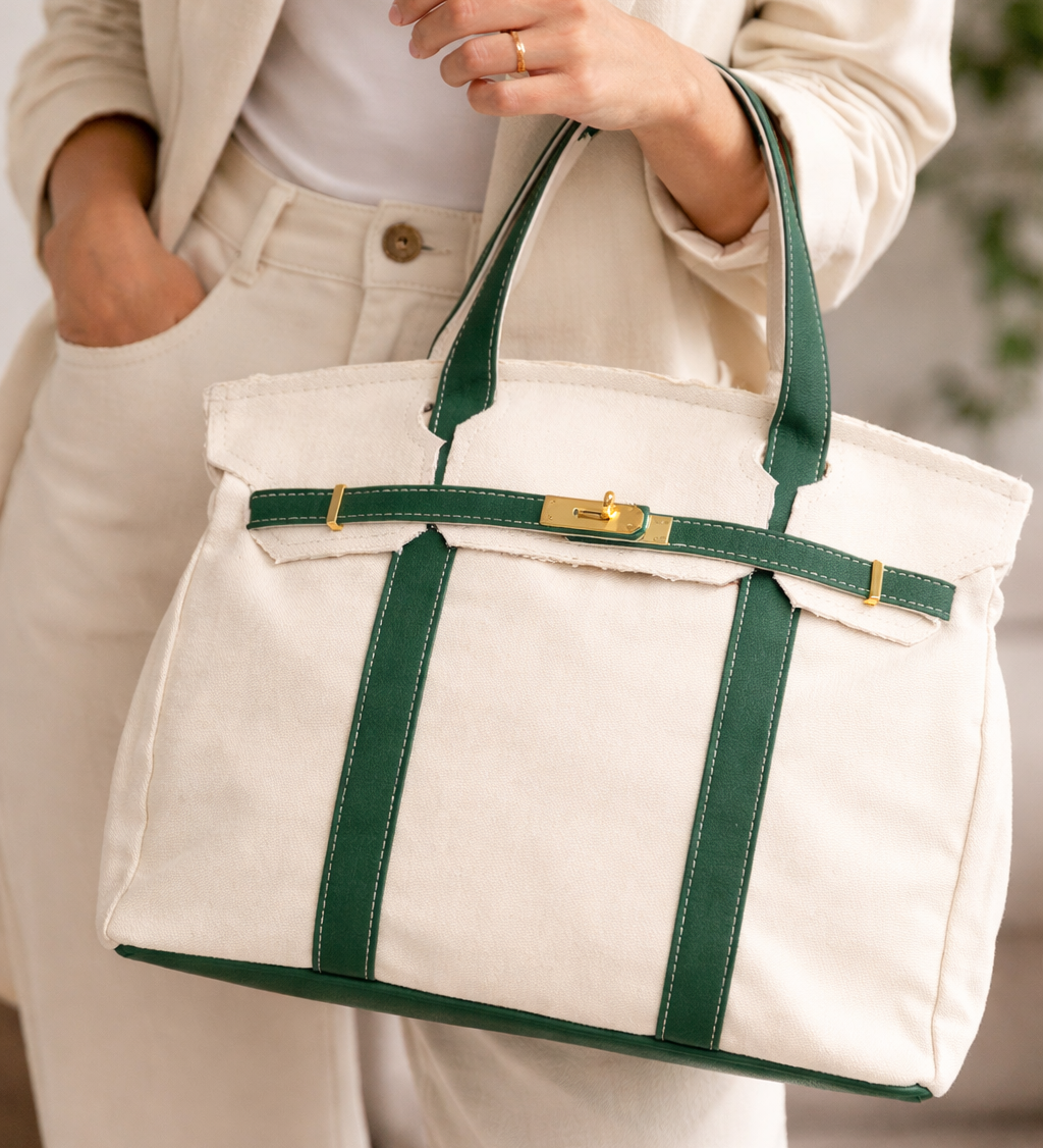Person holding a Heritage stripe tote bag with green straps and trim.