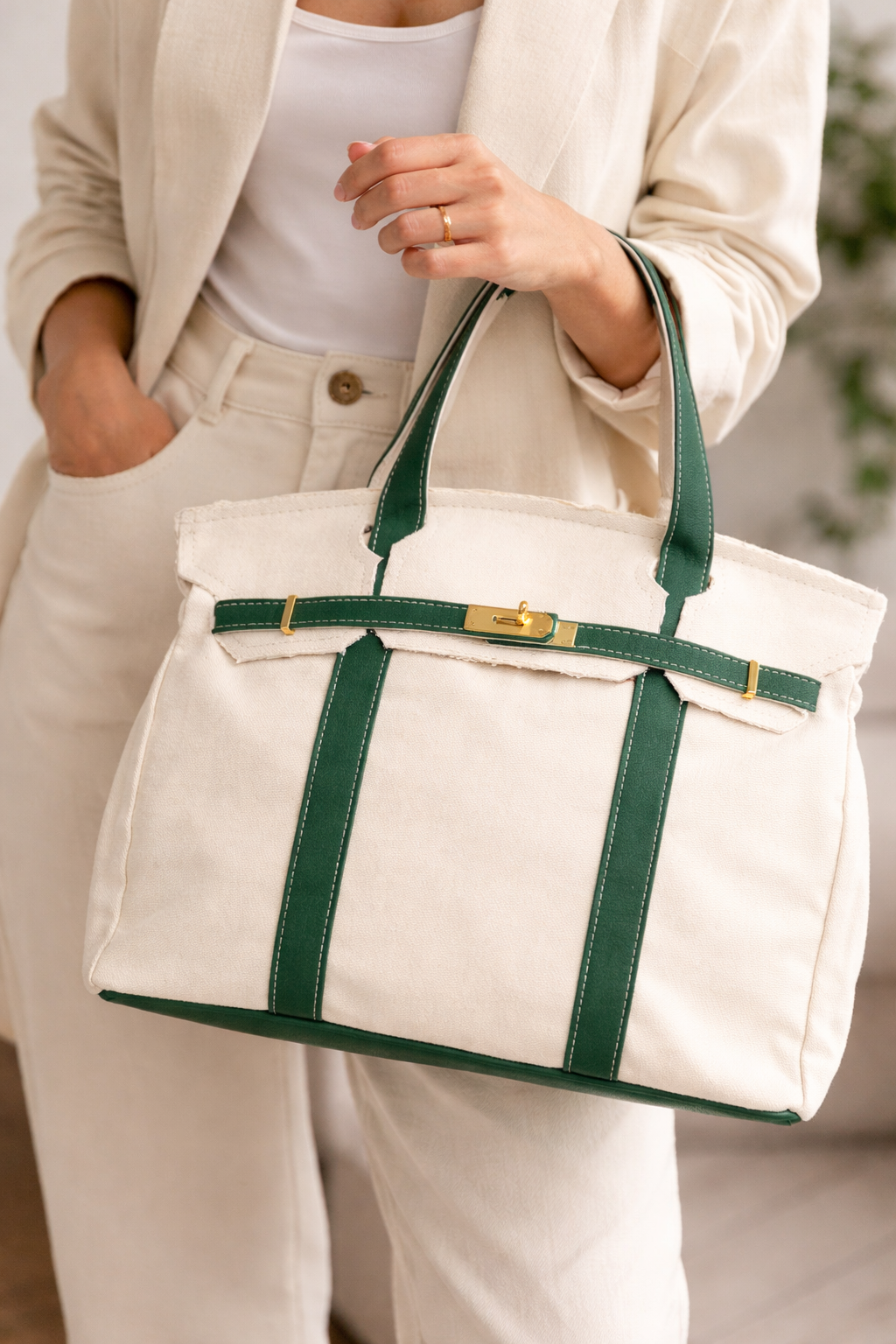 Person holding a Heritage stripe tote bag with green straps and trim.